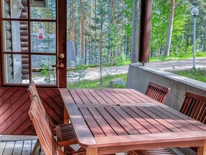 A wooden deck with a table and chairs, overlooking a forested area.