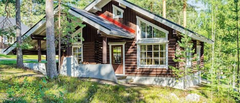 A log cabin with a porch, large windows, and a chimney.