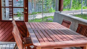 Une terrasse en bois avec une table et des bancs, donnant sur une zone boisée.