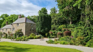 A stone building with a gravel driveway and lush greenery. - The Hideaway & Spa Terrace at Tregoose Old Mill (Newquay)