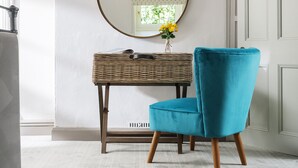 A room with a white wall, a round mirror, a wicker side table, a blue chair, and a white door. - The Hideaway & Spa Terrace at Tregoose Old Mill (Newquay)
