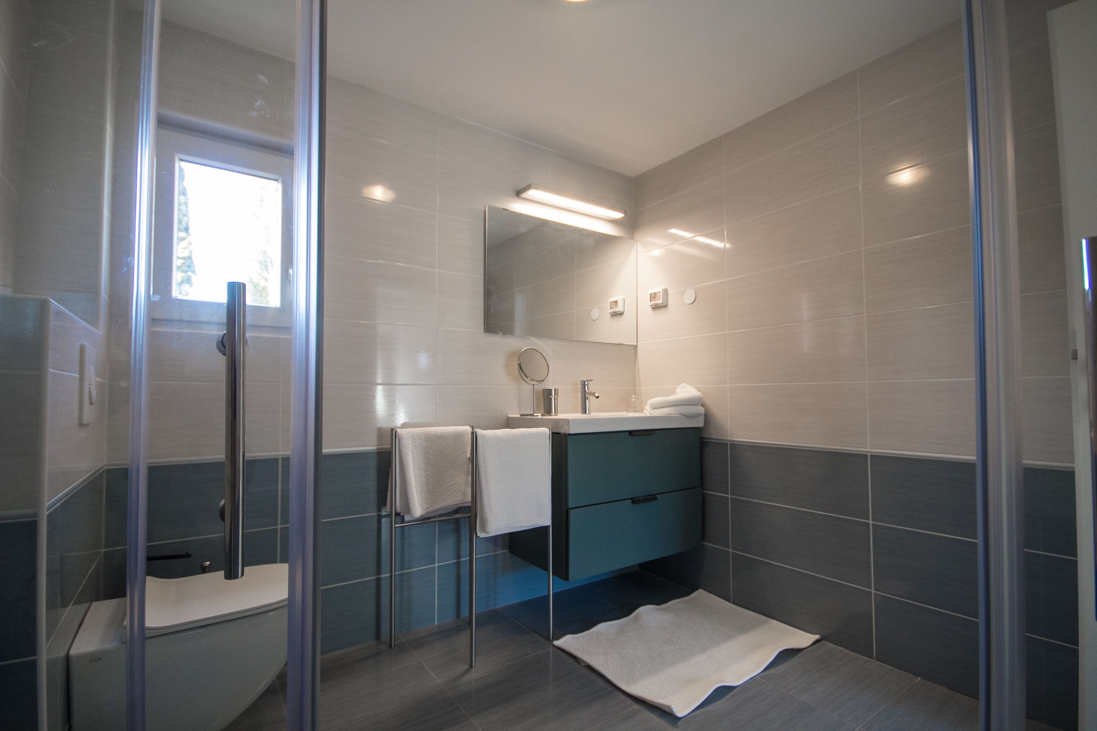 A modern bathroom with a glass shower enclosure, a vanity with a mirror, and a towel rack.