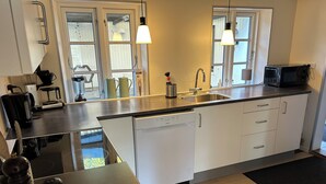 A modern kitchen with a dishwasher, sink, and a microwave. There are two pendant lights above the counter. - Nice holiday home near the beach (Rødekro)