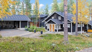 Een chalet met garage, overdekte veranda en een houten deur.