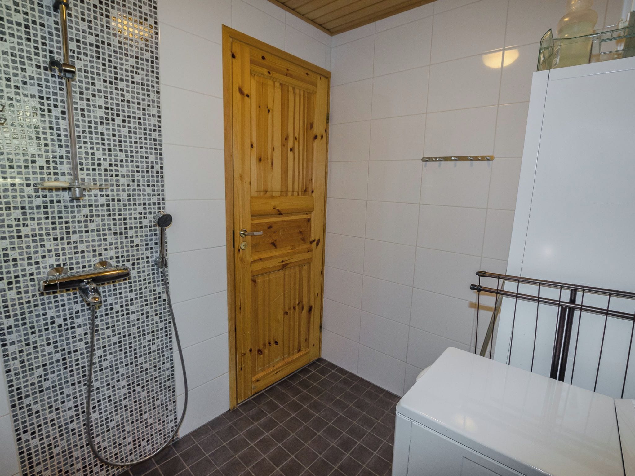Ein Badezimmer mit Holztür, einer Duschkabine mit Glastür und einer weißen Toilette.
