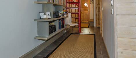 Ein Flur mit einer Holzt Treppe, einem Bücherregal und einer Fußmatte.