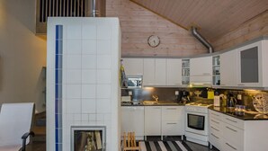 Een moderne keuken met witte kastjes, een ingebouwde oven en een fornuis. Er staat een houten stoel bij een kleintje tafel met een vloerkleed.
