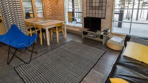 Een gezellig interieur van een chalet met een eethoek, een televisie en een bank.