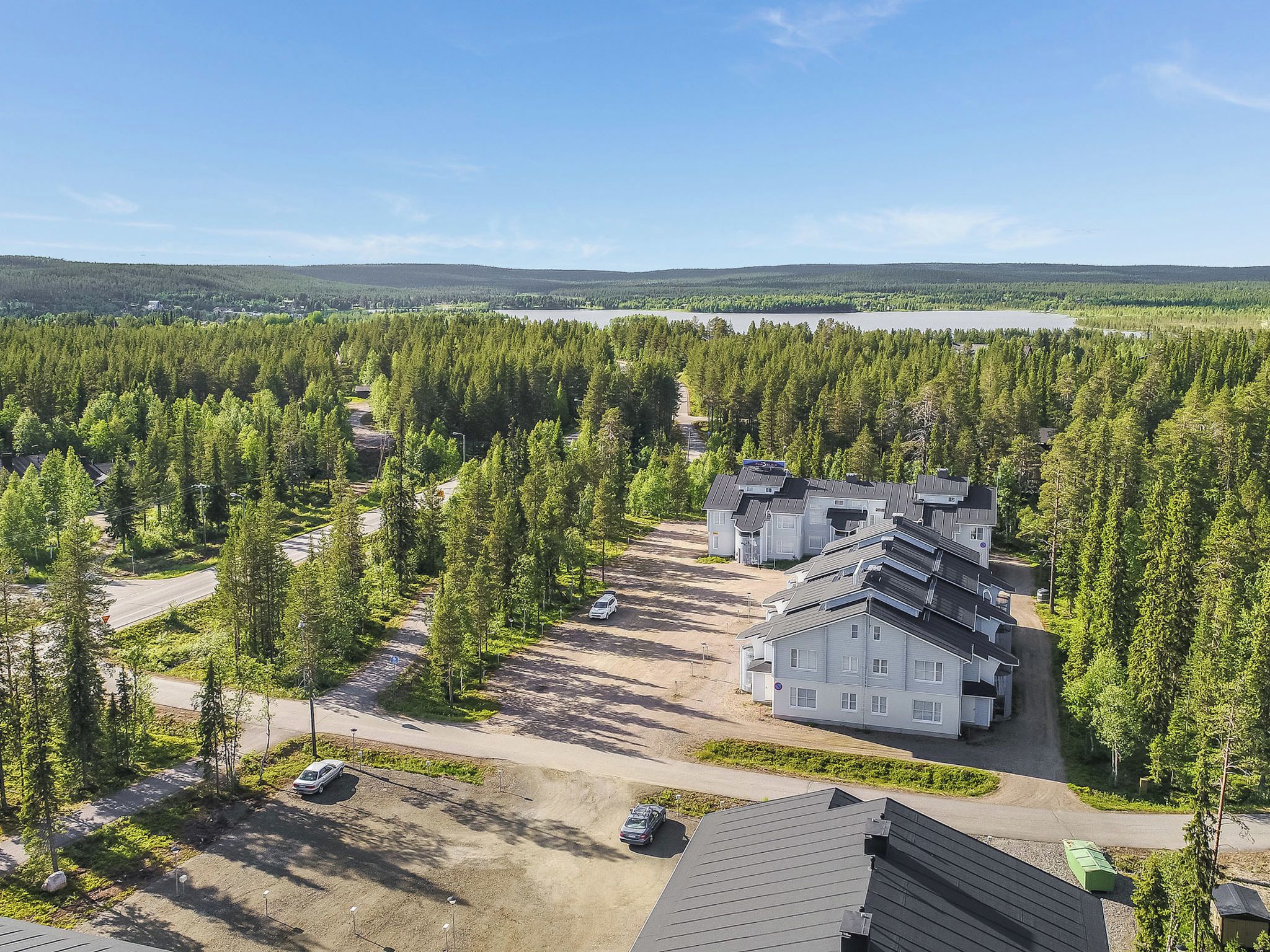 A residential area with multiple houses, a parking lot, and a forested landscape.