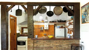 A kitchen with a brick wall, a white stove, and hanging pots. - El Cerrillo - Cerro Negro by Interhome (Orgiva)