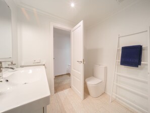 Un baño con lavamanos, inodoro y toallero blancos.