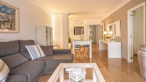 A modern living room with a grey sofa, a coffee table, and a dining area with a white table and chairs. - Maritimo by Interhome (Port d'Alcúdia)