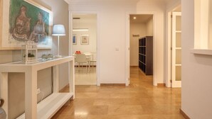 A hallway with a white console table, a painting, and a dark storage unit. - Maritimo by Interhome (Port d'Alcúdia)