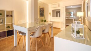 A modern dining area with a glass table, white chairs, and a white cabinet with shelves. - Maritimo by Interhome (Port d'Alcúdia)
