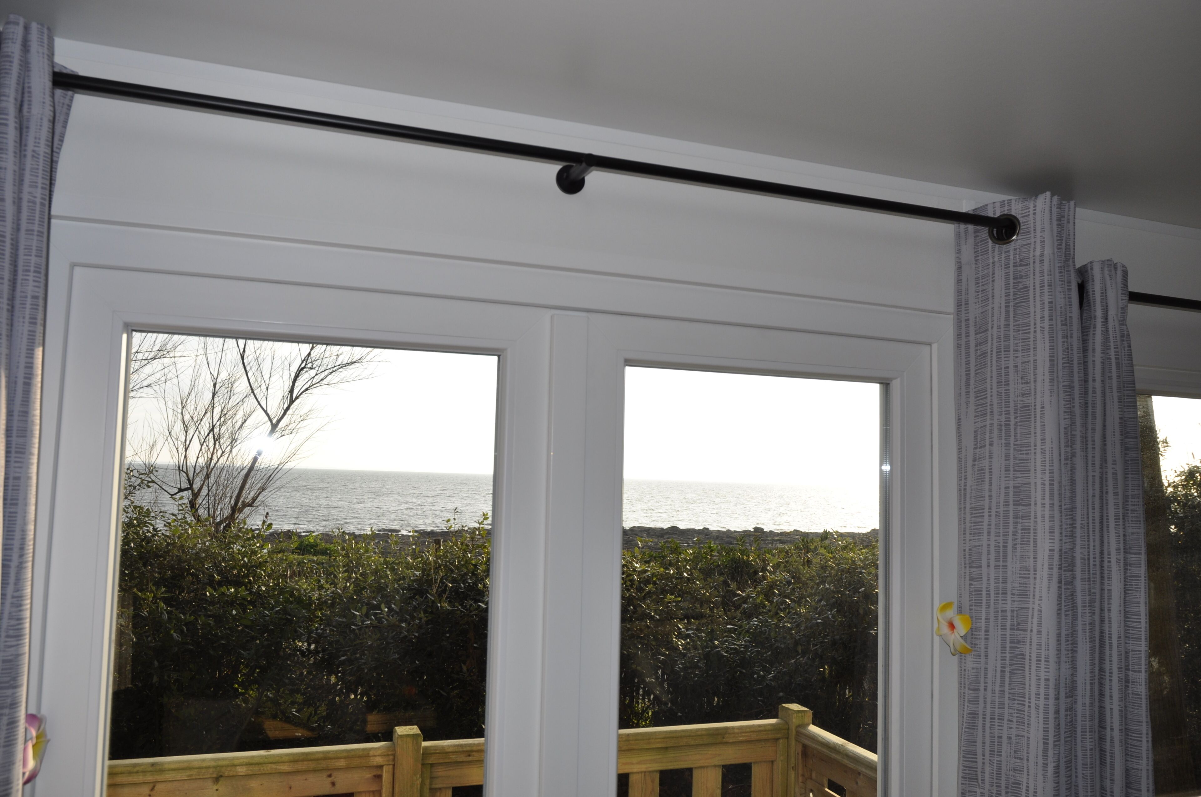 A room with a large sliding glass door leading to a balcony with a view of the sea.