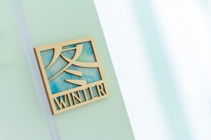 A wooden sign with Chinese characters and the word "WINTER" on a light blue wall. - Story Inn City (Hualien City)