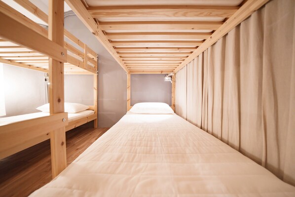 A bunk bed room with wooden beams, a single bed, and a curtain on one side. - Story Inn City (Hualien City)