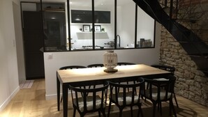 Ein Essbereich mit einem Holztisch und schwarzen Stühlen, einem dekorativen Laternen und Blick auf eine Küche und eine Treppe.