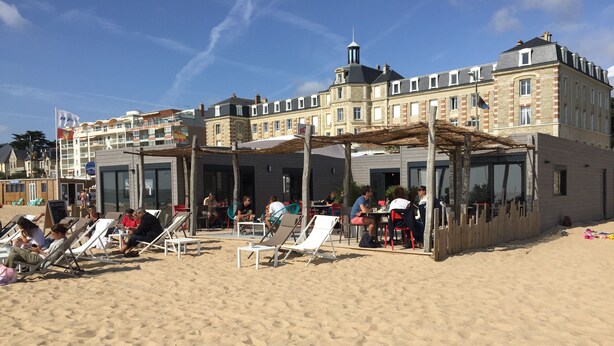 Ein Strandhotel mit Außenbereichen zum Sitzen und einer überdachten Terrasse.