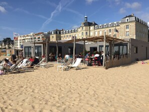 Un hotel frente a la playa con zonas de estar al aire libre y un porche cubierto.
