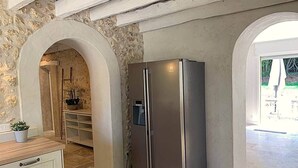 A kitchen with a stainless steel refrigerator, stone walls, and a wooden countertop.