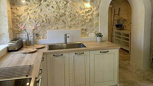 A kitchen with a stone wall, a sink, cabinets, and a toaster.