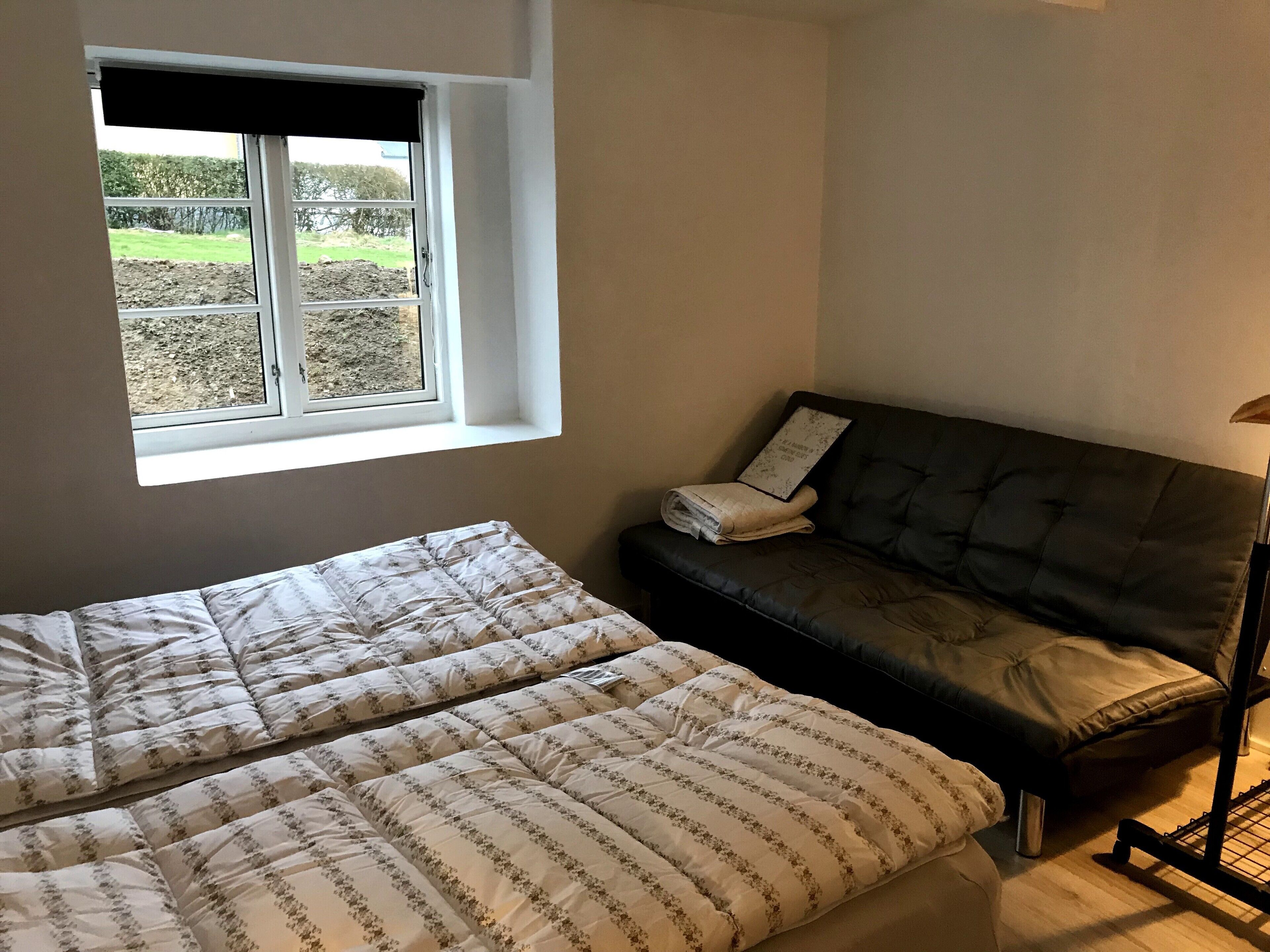 Een slaapkamer met een bed, een bank, een raam en een lamp.