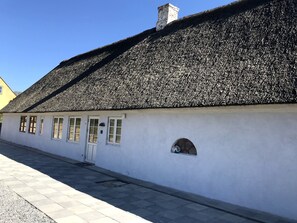 A traditional building with a steeply pitched roof and a small arched window. - Newly renovated cottage near the beach (Rødekro)