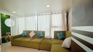 Una sala de estar con un sofá modular, un espejo redondo y una pared verde de acento.