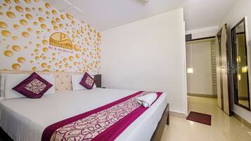A hotel room with a large bed, a decorative wall with circular patterns, and a visible door leading to another room.