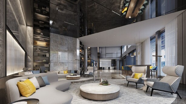 En rummelig lobby med et moderne design, med et centralt siddeområde med sofaer og lænestole, et marmorbord og et stort, åbent område med en reception i baggrunden.