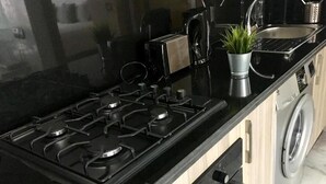 Une cuisine avec un four noir, un grille-pain, un évier et un lave-linge.
