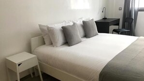 Une chambre bien rangée, avec un lit, une table de chevet, un bureau et une chaise.