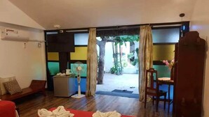 Habitación de hotel con cama, escritorio, silla, ventilador y vistas al exterior.