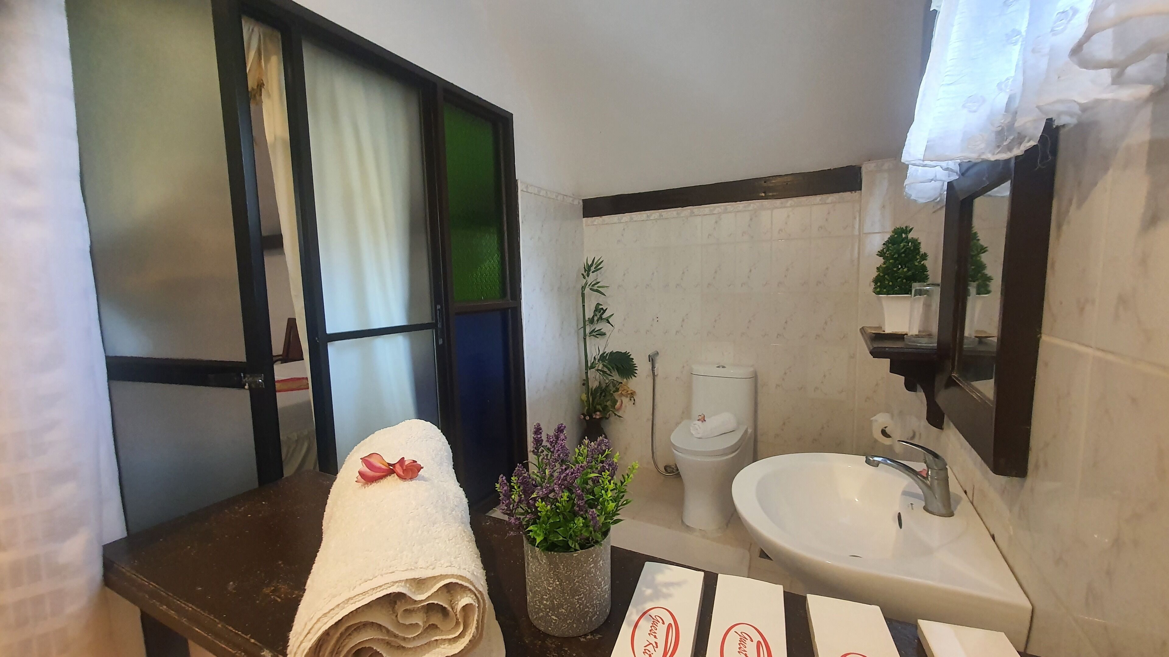A bathroom with a sink, toilet, and window with curtains.