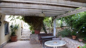 A covered patio with a table and benches, surrounded by potted plants and a stone staircase. - villa ground floor apartment (Dénia)