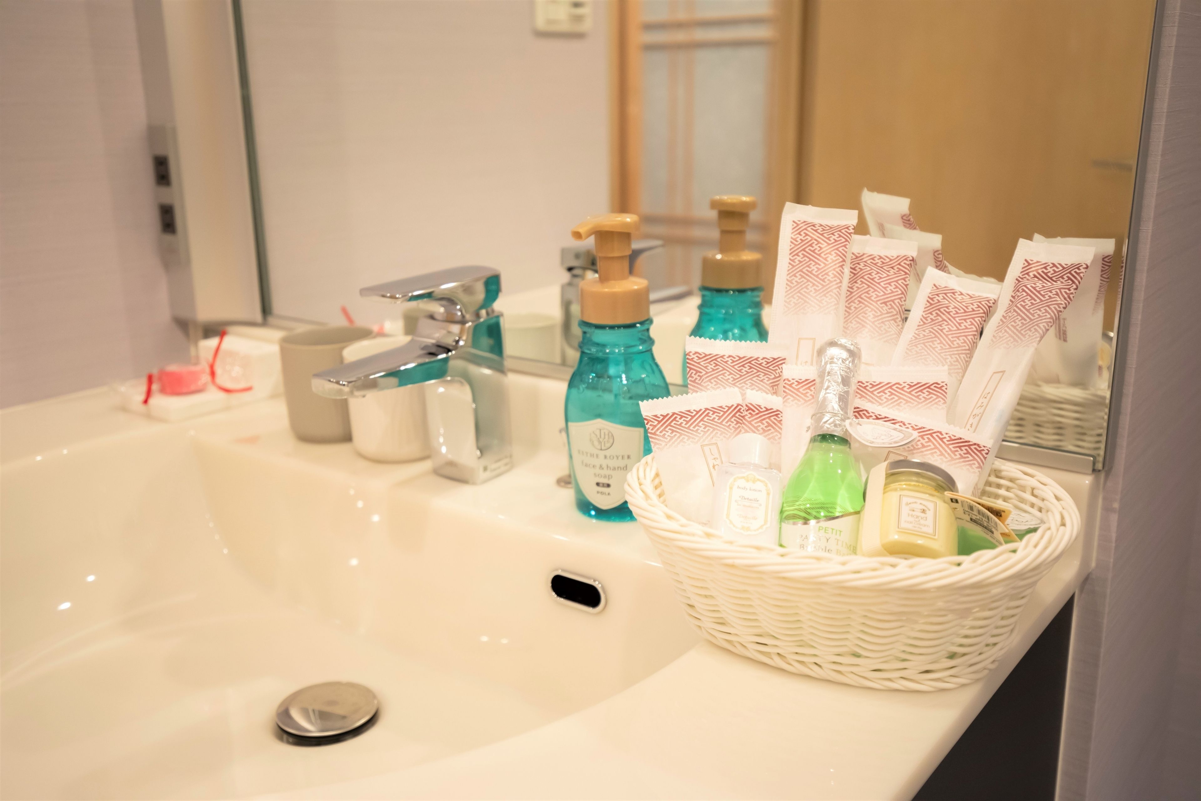 A bathroom sink with toiletries and a basket of items.