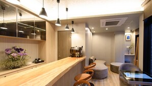 A modern bar area with wooden counter, bar stools, and pendant lighting.