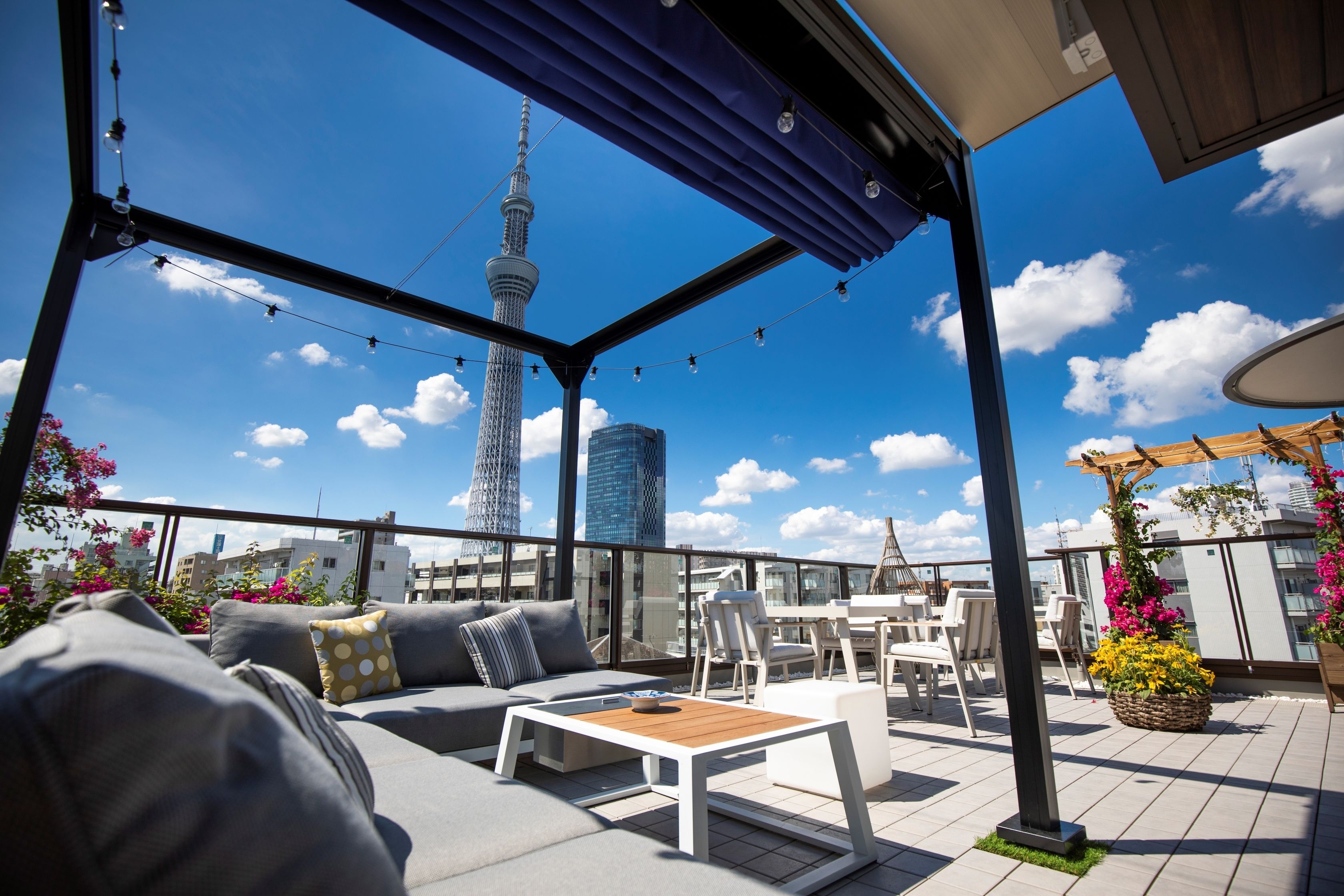 A rooftop terrace with a view of the tower, seating, and potted plants.