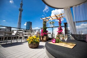Una terraza en la azotea con zona de estar, una pérgola de madera con flores y vistas a la Torre Eiffel.