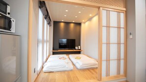 A hotel room with a sliding shoji screen, a television, and a minibar.