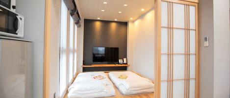 A hotel room with a sliding shoji screen, a television, and a minibar.