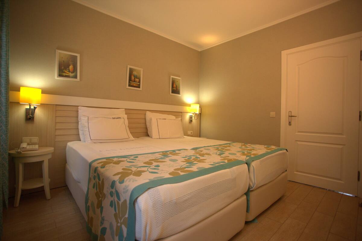 A hotel room with a bed, two bedside lamps, a nightstand, and a door.
