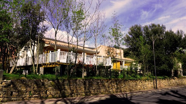 A two-story building with a balcony and a stone wall in front. - New residence, The Manaka, The Rose of the Sands, calm and rest (lamalou les bains)