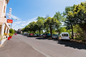 A street lined with parked cars and a hotel with a 'Contact Hotel' sign. - Les Messageries (Saint-Flour)