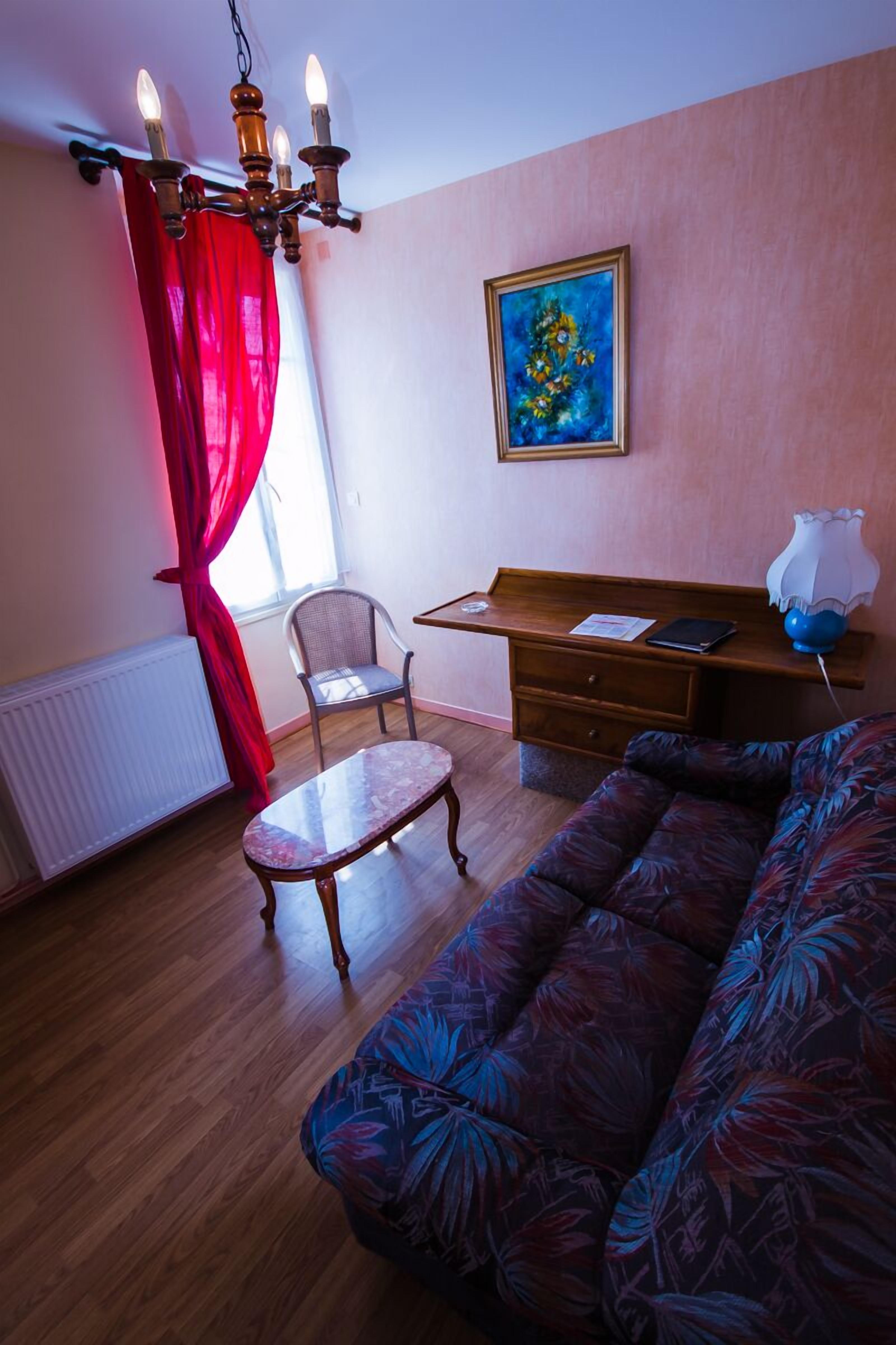 Una sala de estar con un sofá, una silla, una mesa, un escritorio y un cuadro en la pared.