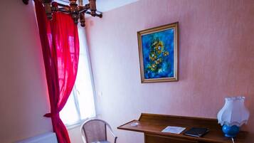 Una sala de estar con un sofá, una silla, una mesa, un escritorio y un cuadro en la pared.