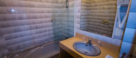 A bathroom with a bathtub, a sink, and a mirror.