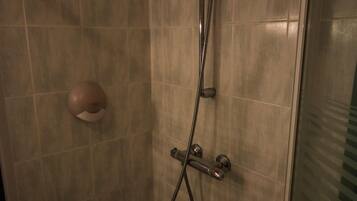 A shower with a handheld showerhead and a wall-mounted faucet.