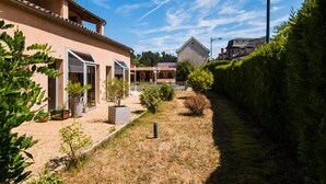 A residential area with a house featuring a patio, potted plants, and a well-maintained lawn. - Les Messageries (Saint-Flour)